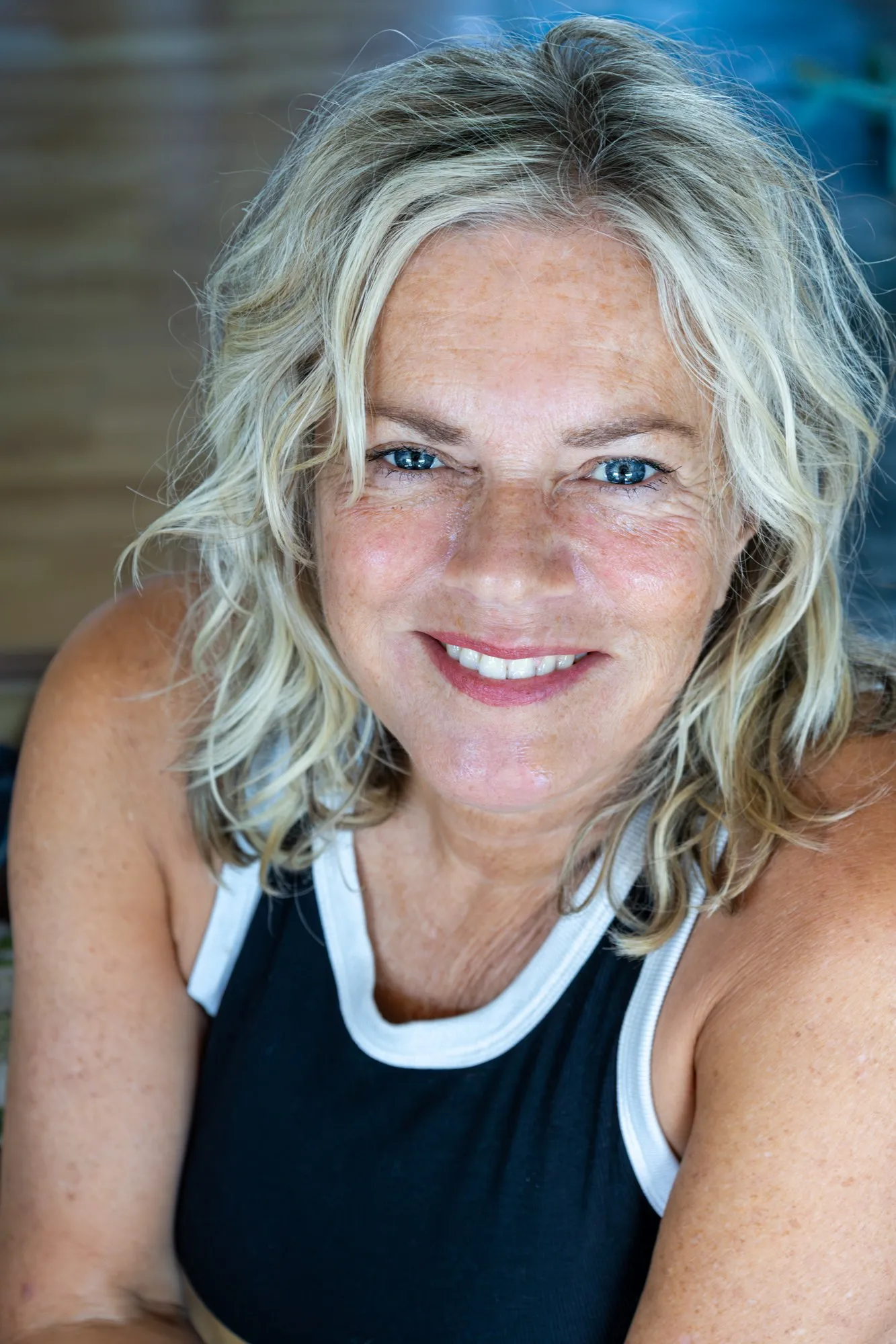 A blonde woman smiles in bright natural light.