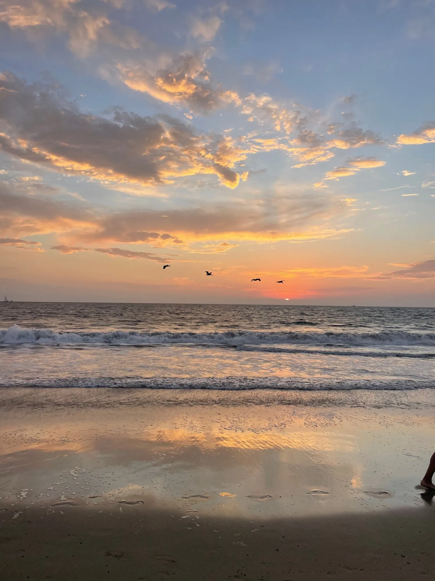 A broad evening sky and the shoreline meet in a luminous reflection.