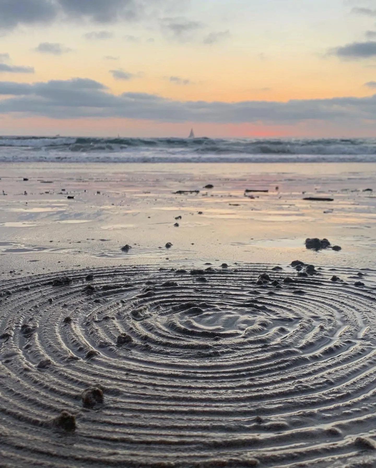 A circular design in the sand echoes the movement of the tide.