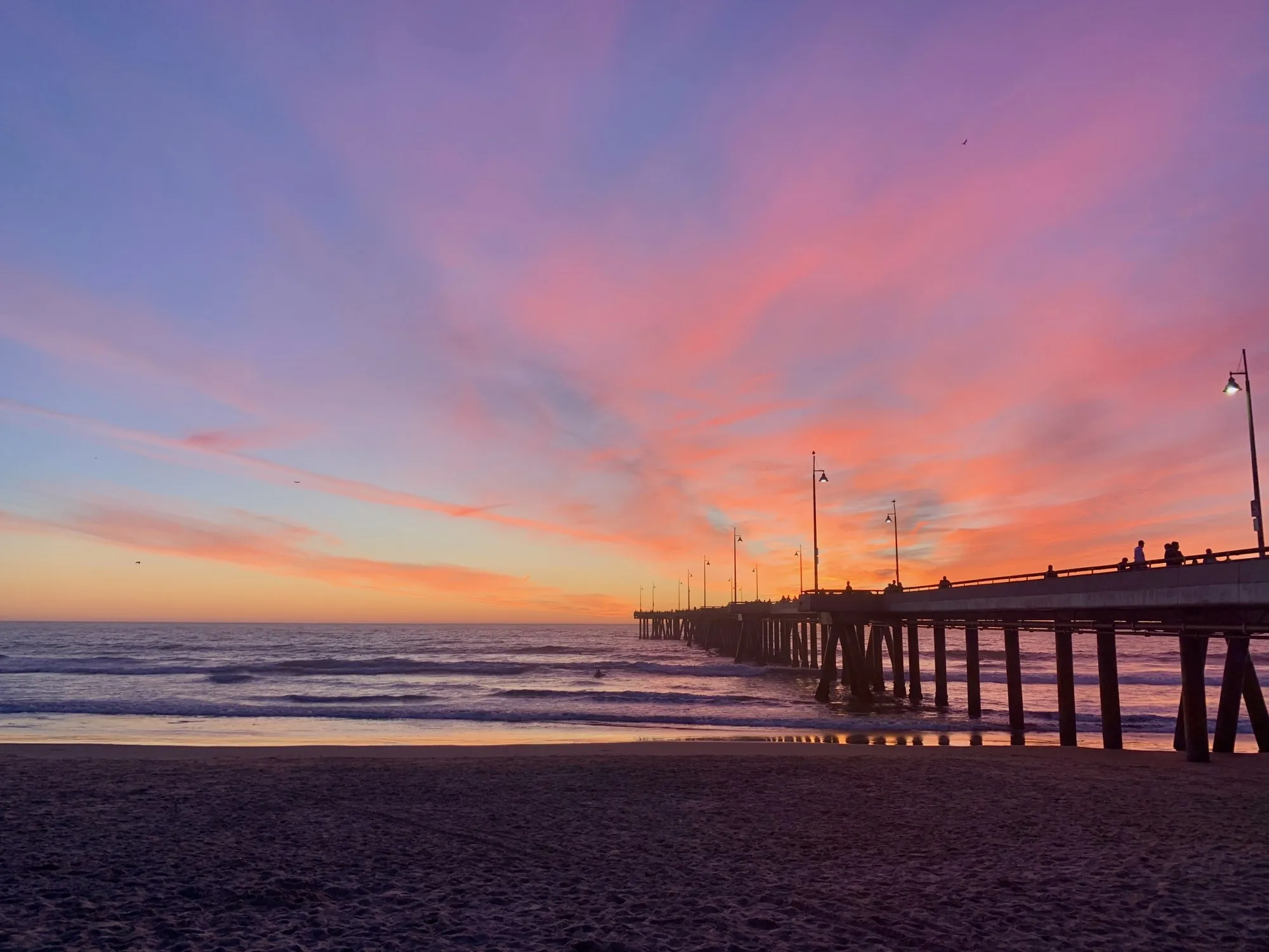 A low pier silhouetted beneath a pink and blue evening sky