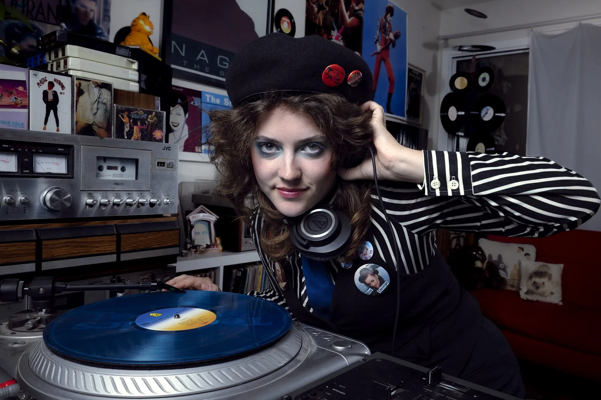A DJ leaning over a turntable surrounded by records and equipment