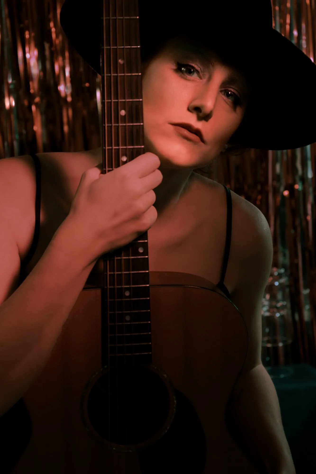 A musician holding a guitar in a warmly lit interior