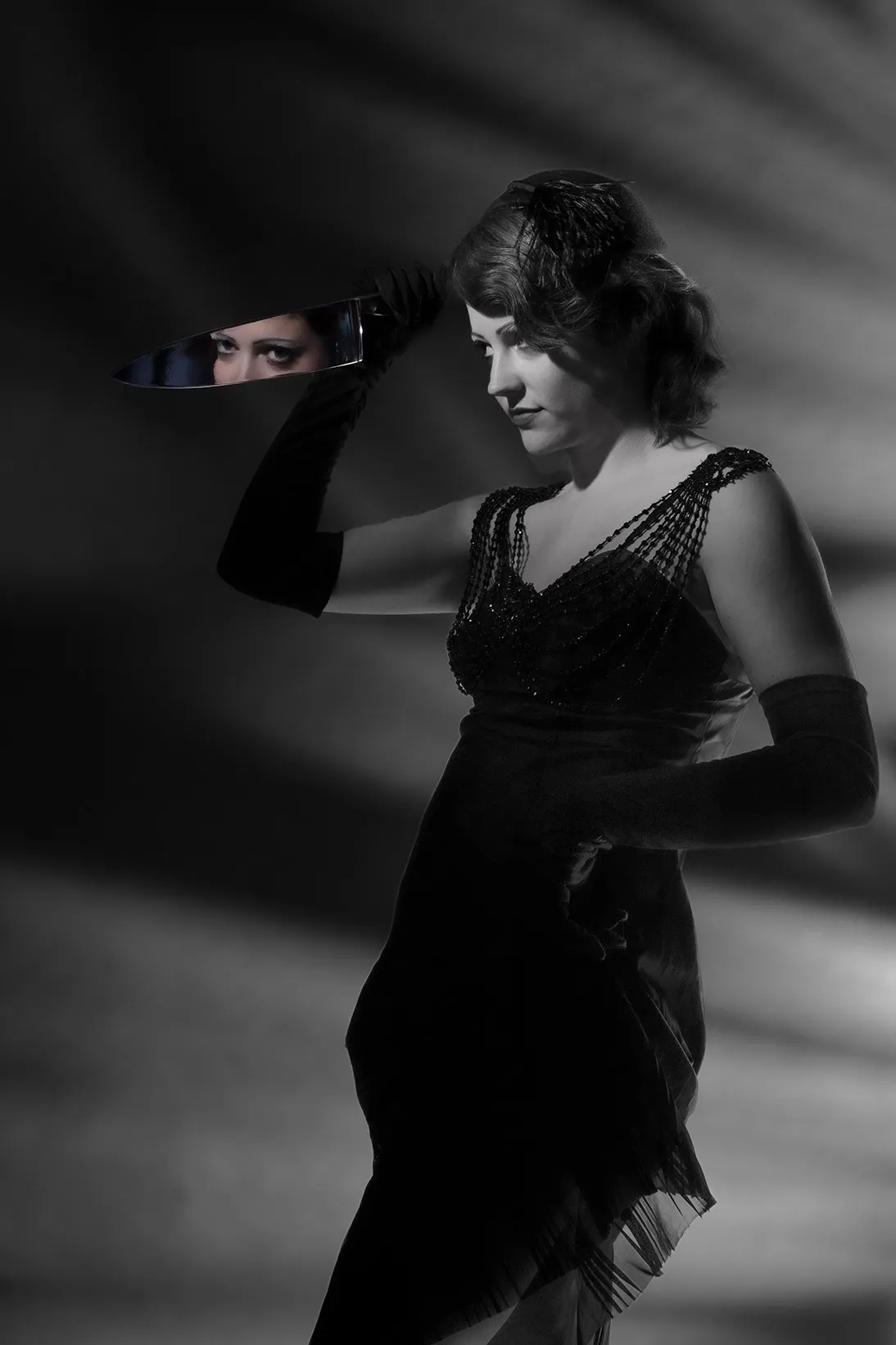 Black-and-white portrait of a woman in a dark dress with a strong diagonal shadow