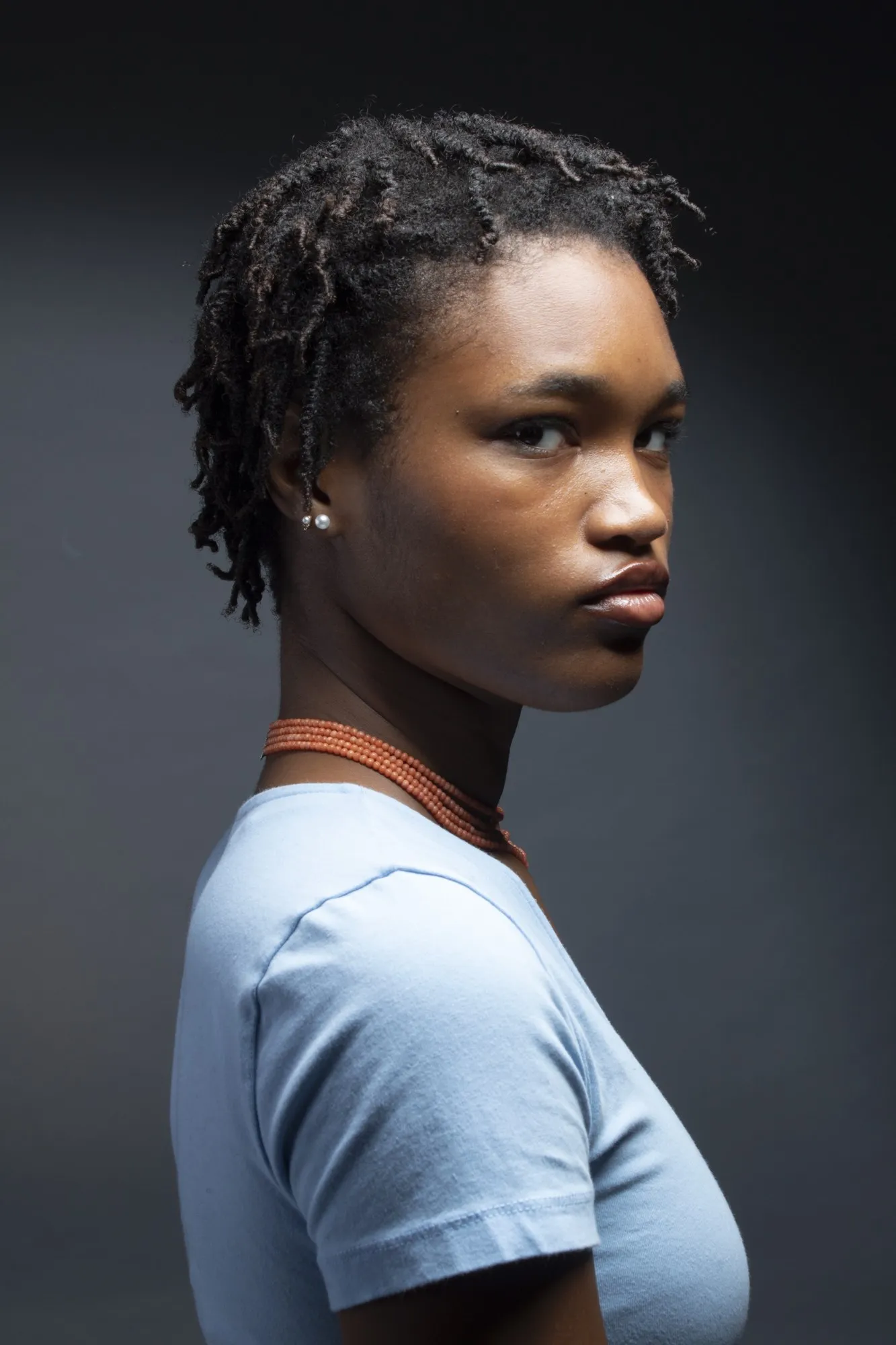 Studio portrait of a woman in a pale blue top turned toward the camera