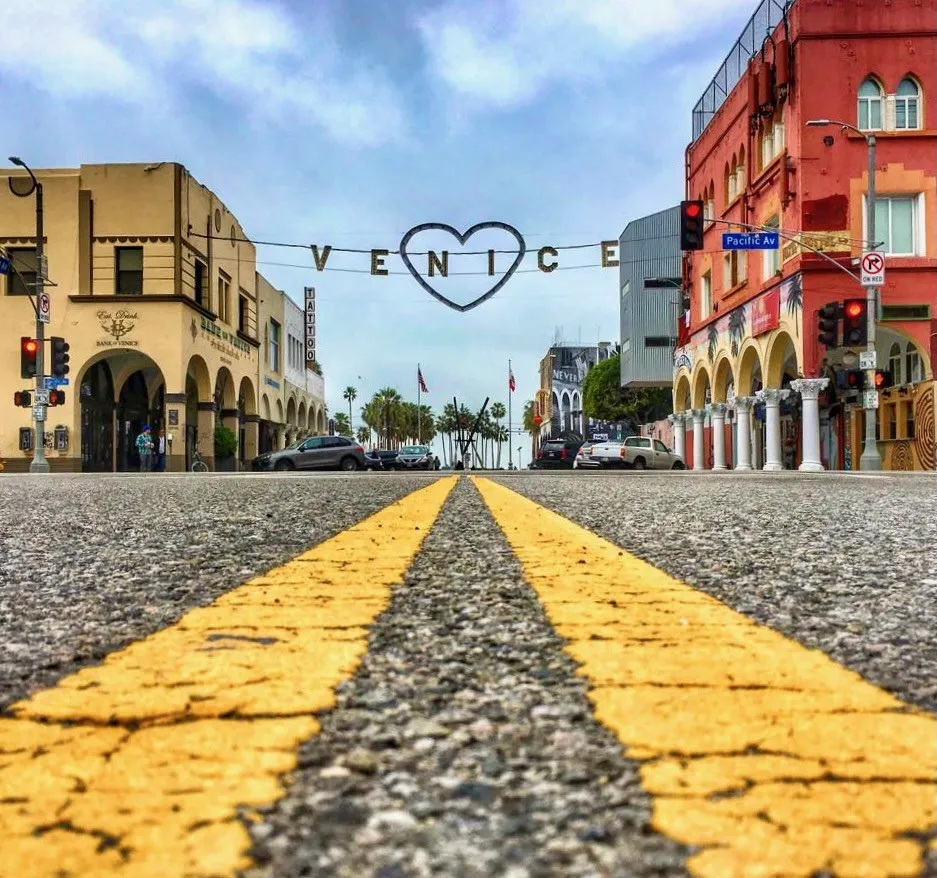 A low view of yellow road markings leading toward colorful city buildings