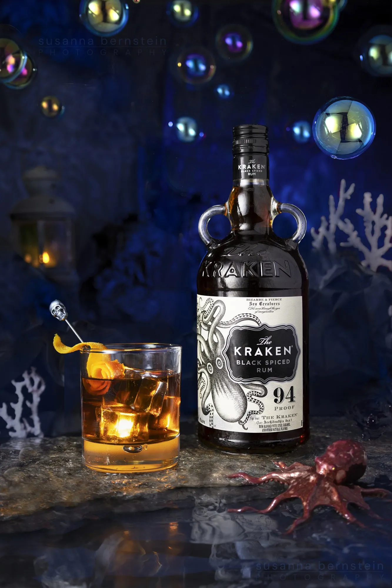 A dark rum bottle and glass in a warmly lit still life