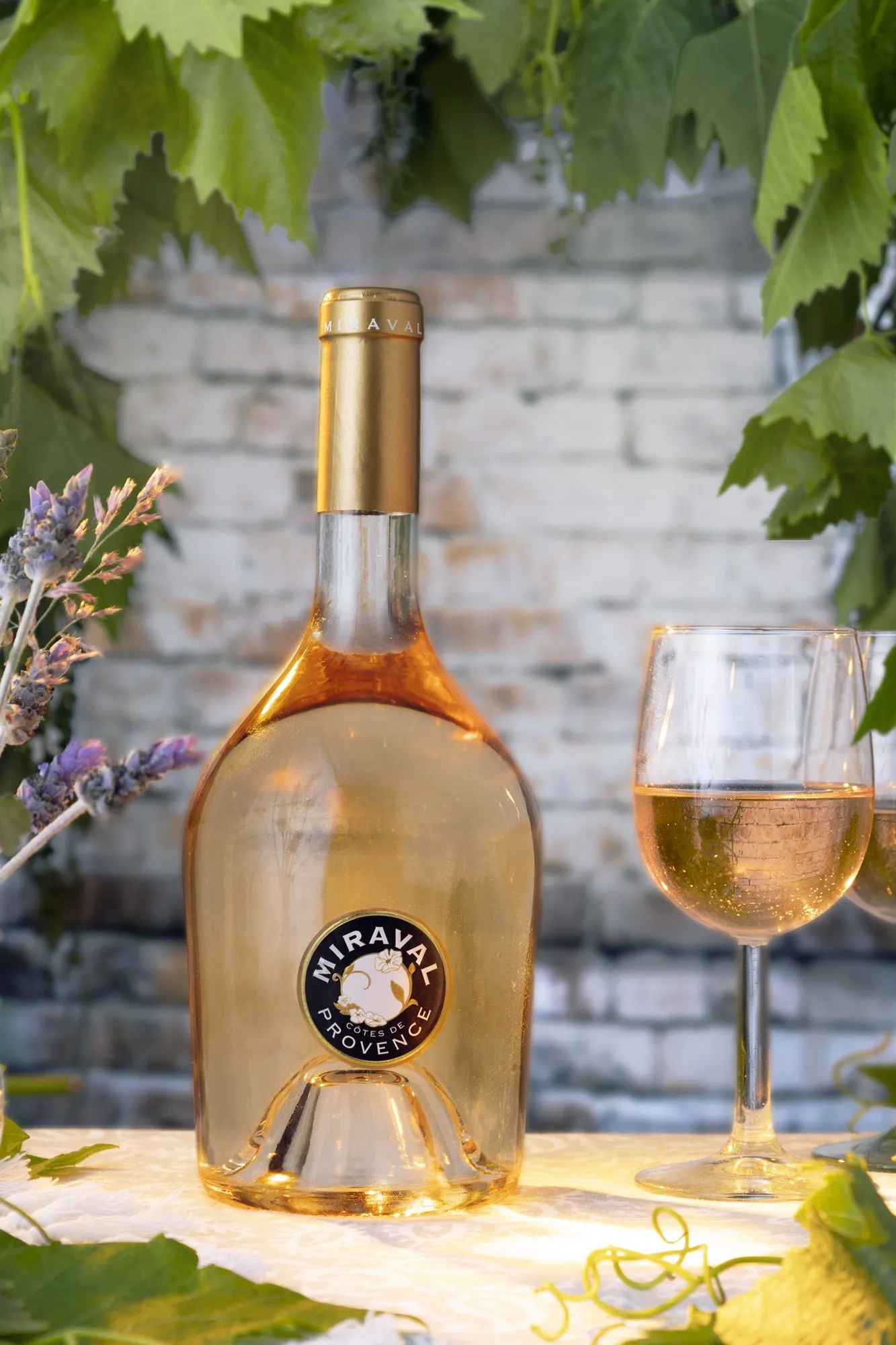 A pale wine bottle and glasses on a sunlit tabletop