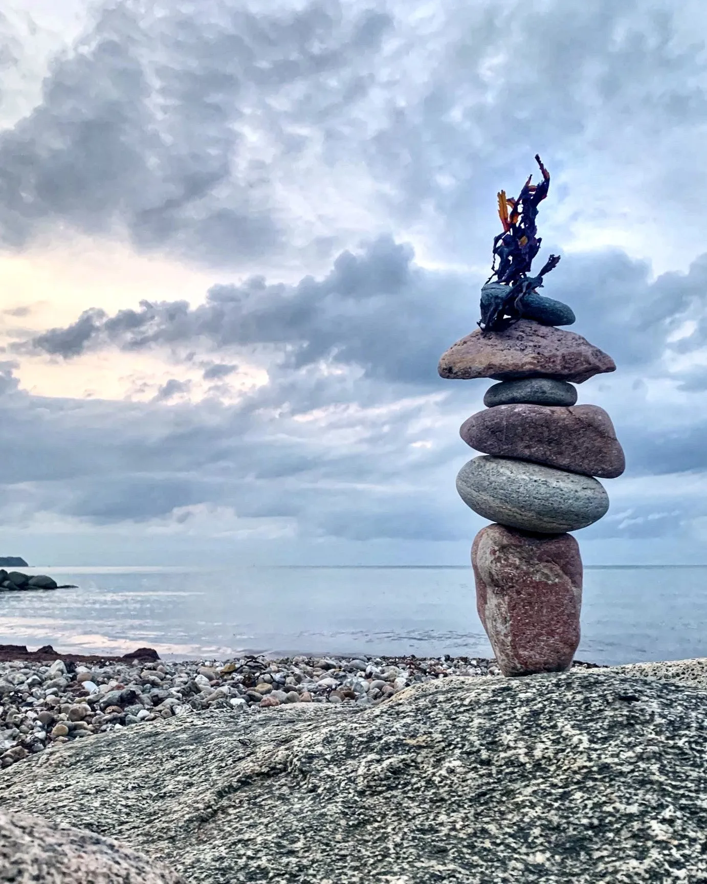 A narrow stone tower topped with a branching flourish beneath textured clouds