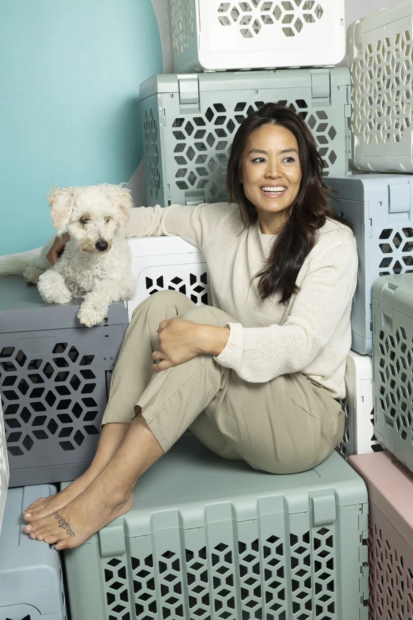 A woman sits on patterned outdoor steps beside a small white dog.